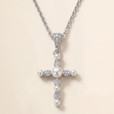 A silver cross pendant with pearls and diamonds attached to it.