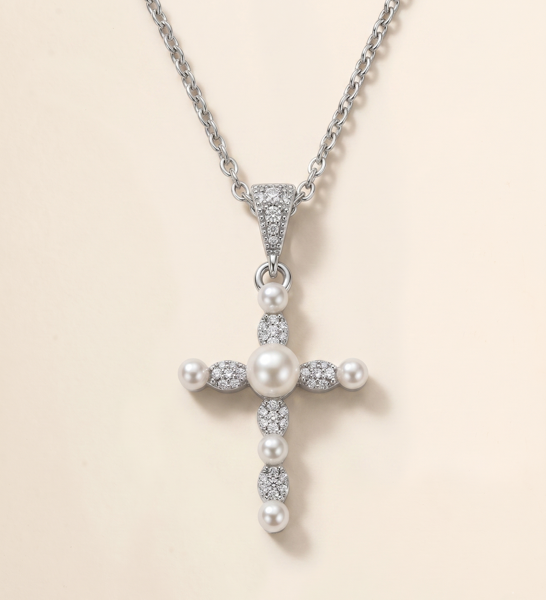 A silver cross pendant with pearls and diamonds attached to it.