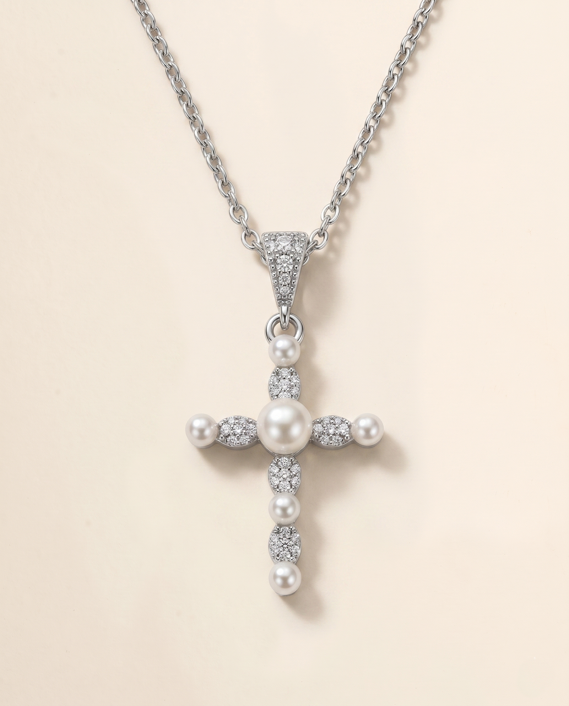 A silver cross pendant with pearls and diamonds attached to it.