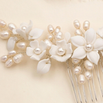 A close-up view of a delicate white flower-shaped hair accessory adorned with numerous small pearls.