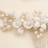 A close-up view of a delicate white flower-shaped hair accessory adorned with numerous small pearls.