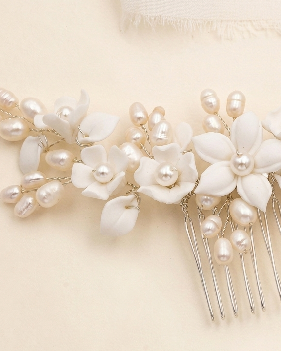 A close-up view of a delicate white flower-shaped hair accessory adorned with numerous small pearls.