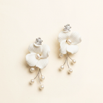 A pair of elegant white earrings with delicate flower-like designs and dangling pearls.