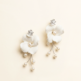 A pair of elegant white earrings with delicate flower-like designs and dangling pearls.