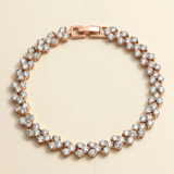 A delicate gold-toned bracelet adorned with numerous small, clear diamonds arranged in a circular pattern.