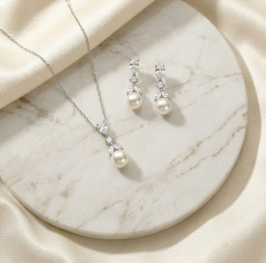 A necklace with a pendant and earrings are displayed on a marble surface.