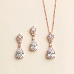 A necklace and earrings set with a pendant and dangling earrings, all featuring large, clear gemstones.