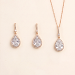 A set of three gold-colored earrings and a necklace with large, clear gemstone pendants.