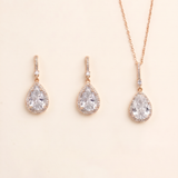 A set of three gold-colored earrings and a necklace with large, clear gemstone pendants.