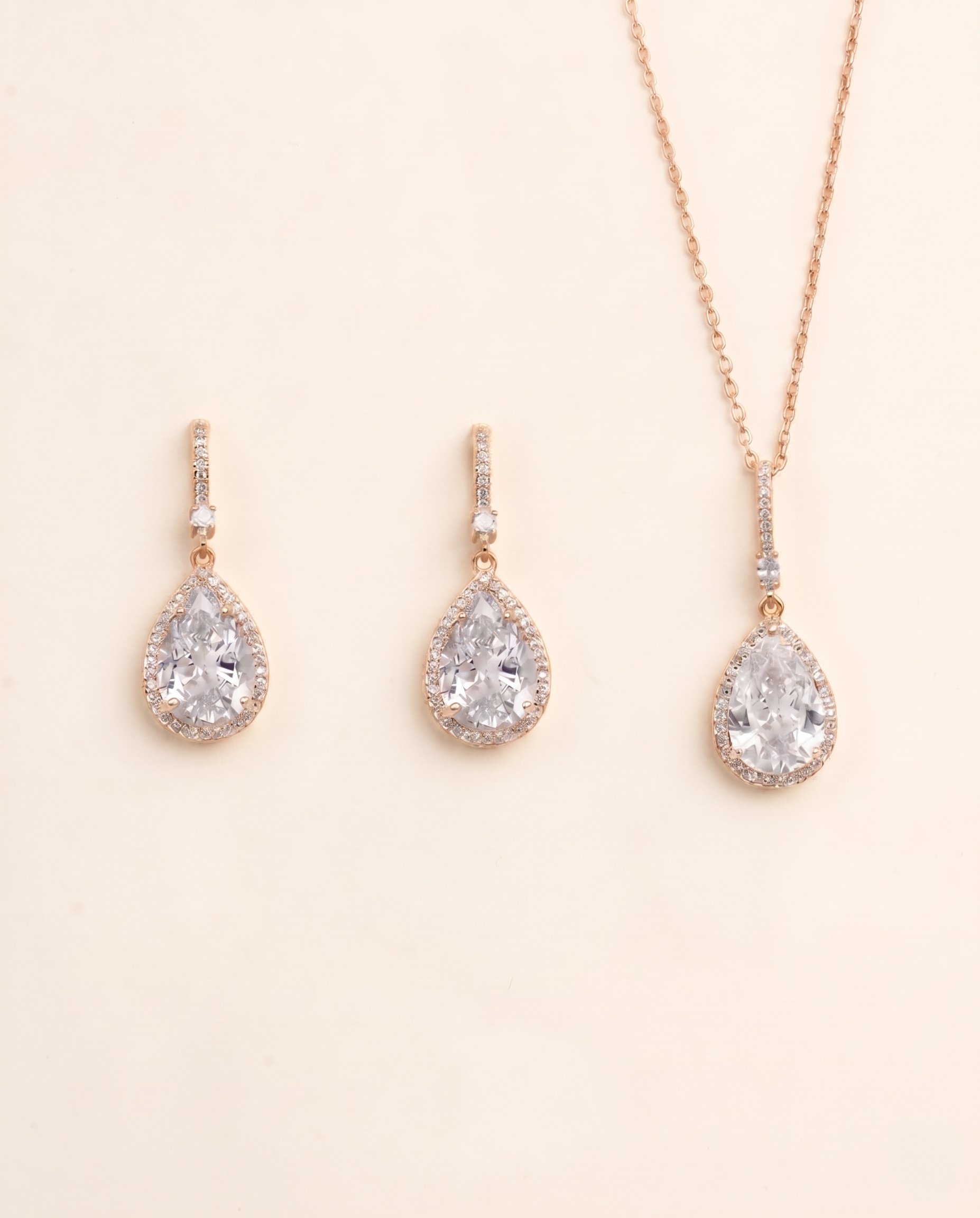 A set of three gold-colored earrings and a necklace with large, clear gemstone pendants.