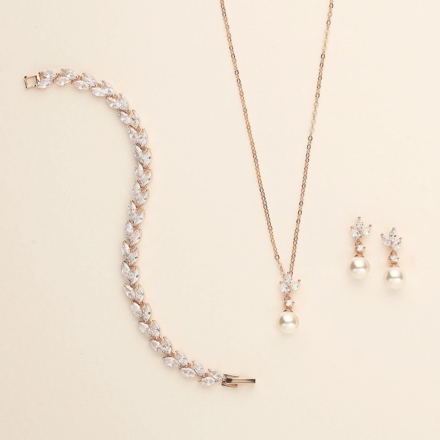 a necklace, bracelet, and earring set on a white surface