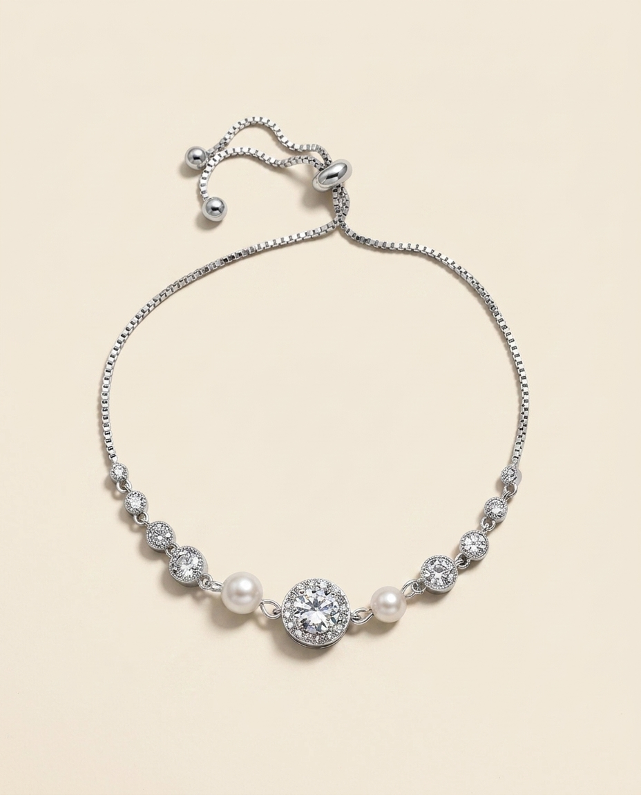 A silver bracelet with a row of pearls and a large central diamond.