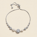 A silver bracelet with a row of pearls and a large central diamond.