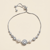 A silver bracelet with a row of pearls and a large central diamond.