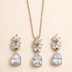 A gold necklace with a pendant and earrings featuring large, clear gemstones.
