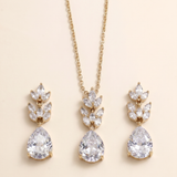 A gold necklace with a pendant and earrings featuring large, clear gemstones.