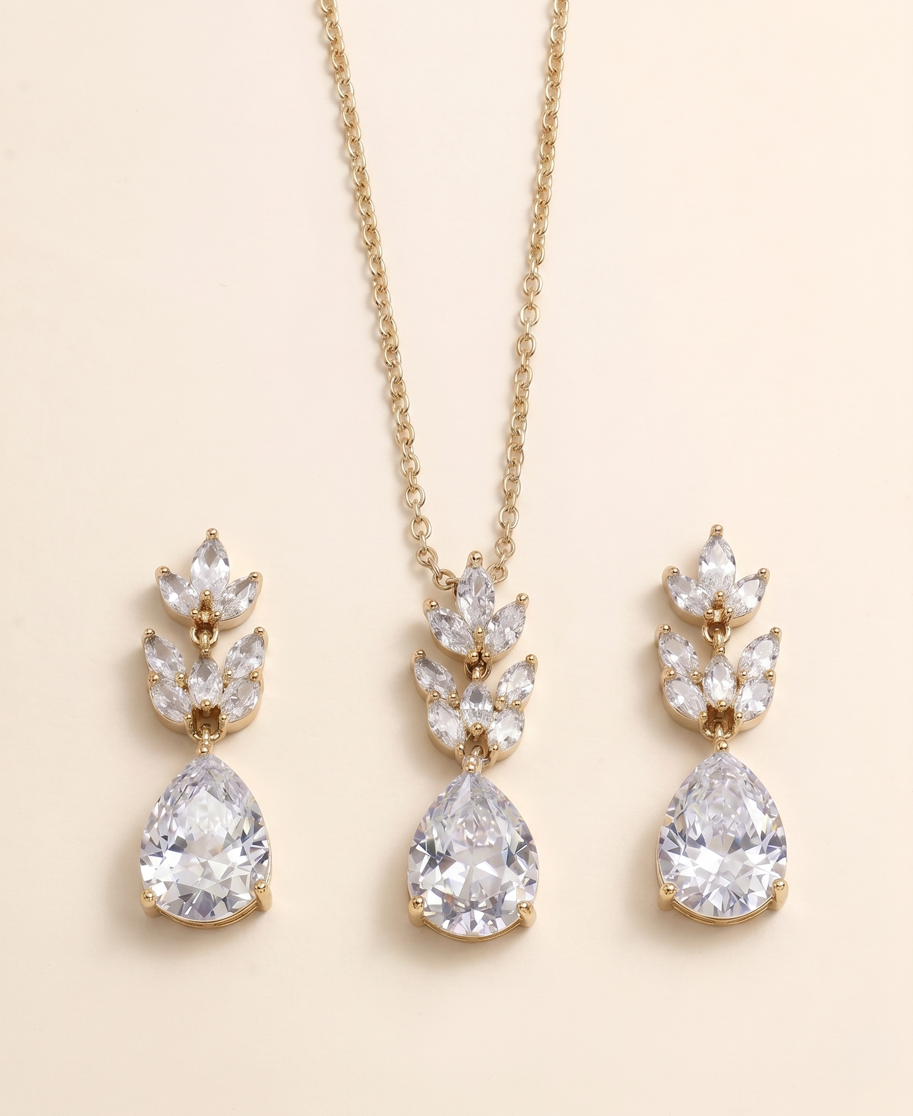 A gold necklace with a pendant and earrings featuring large, clear gemstones.