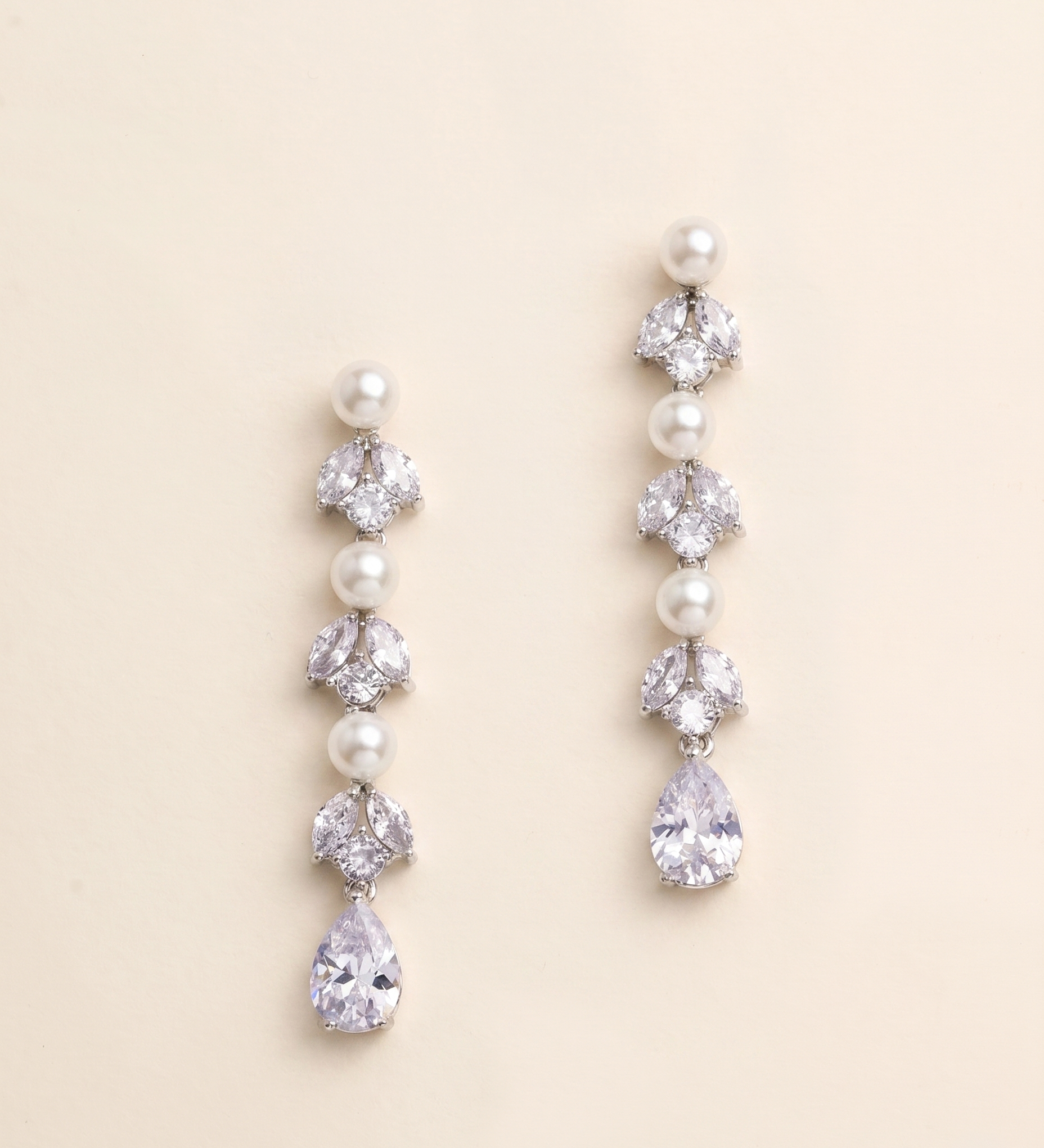 A pair of elegant earrings with pearls and crystals, featuring a row of pearls and a single crystal at the end of each earring.