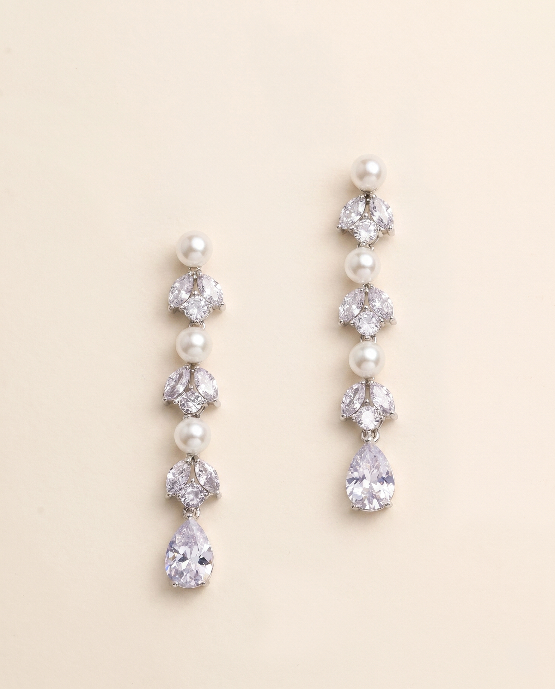 A pair of elegant earrings with pearls and crystals, featuring a row of pearls and a single crystal at the end of each earring.