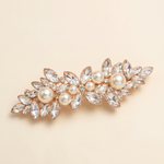 A decorative hair clip adorned with numerous crystal and pearl embellishments.