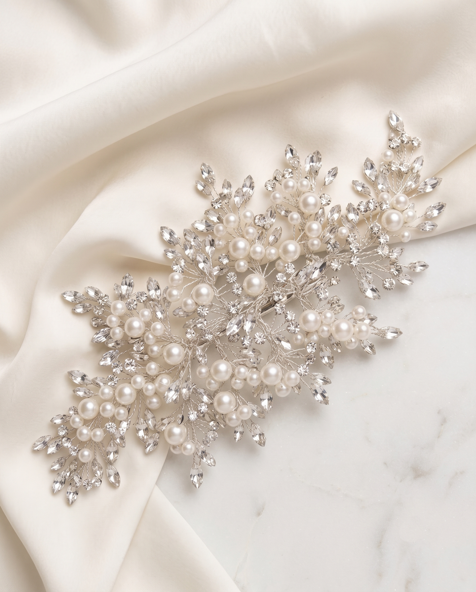 a delicate and elegant piece of jewelry, adorned with numerous pearls and sparkling crystals, resting on a white fabric surface.