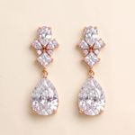 A pair of elegant earrings with large, clear gemstones set in a rose gold-colored metal.