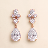 A pair of elegant earrings with large, clear gemstones set in a rose gold-colored metal.