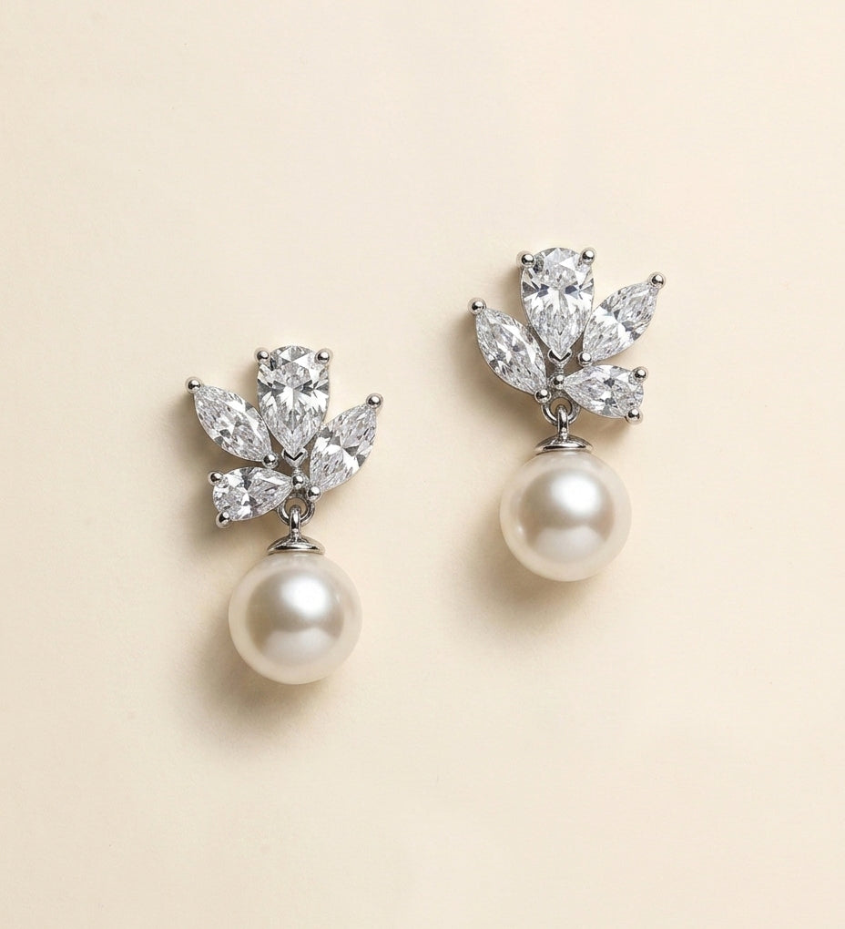 A pair of elegant earrings with a pearl and a cluster of diamonds as the main components.