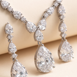 A close-up image of a necklace and earrings featuring a collection of large, sparkling diamonds.