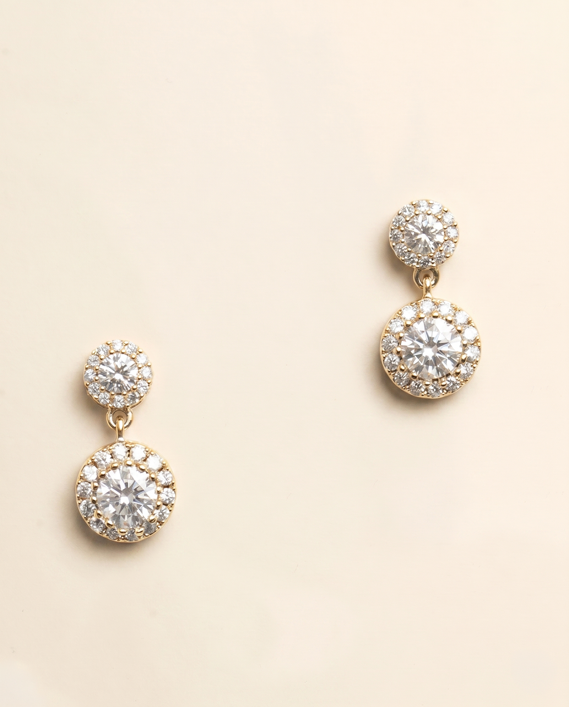 A pair of elegant gold earrings with large, clear gemstones set in a circular design.