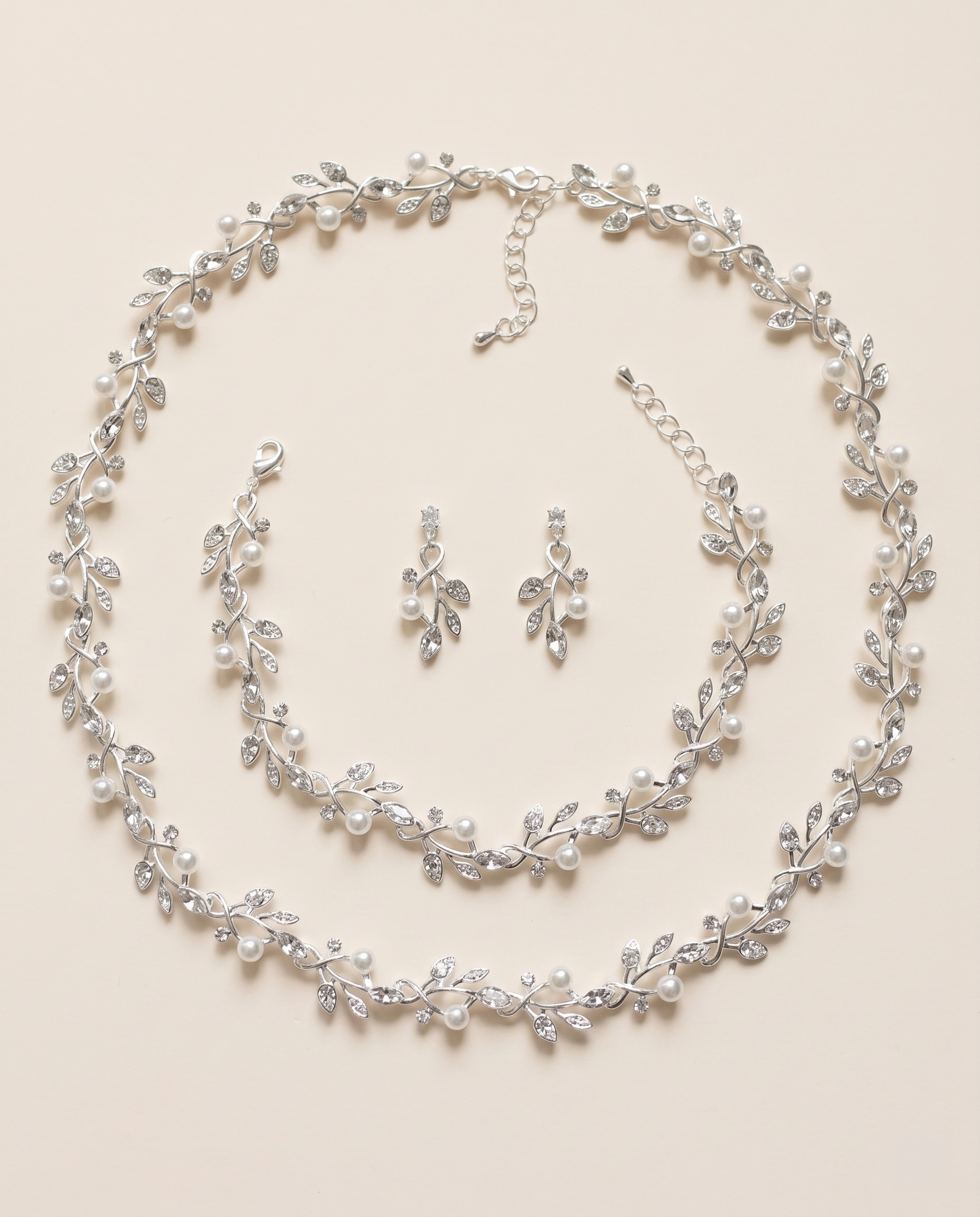 A delicate necklace and earrings set adorned with small, sparkling crystal leaves and pearls.