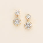 A pair of gold earrings with large, clear gemstones set in a circular design.