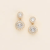 A pair of gold earrings with large, clear gemstones set in a circular design.