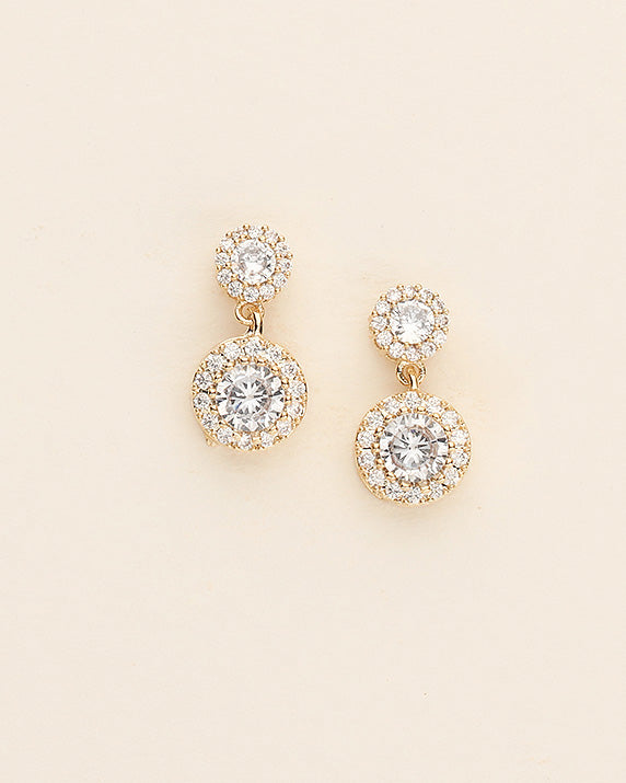 A pair of gold earrings with large, clear gemstones set in a circular design.