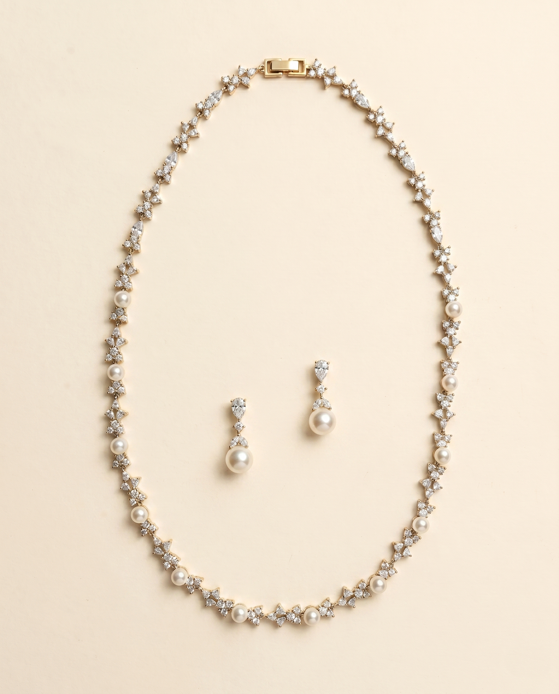 A gold necklace and earrings set are displayed against a light beige background.