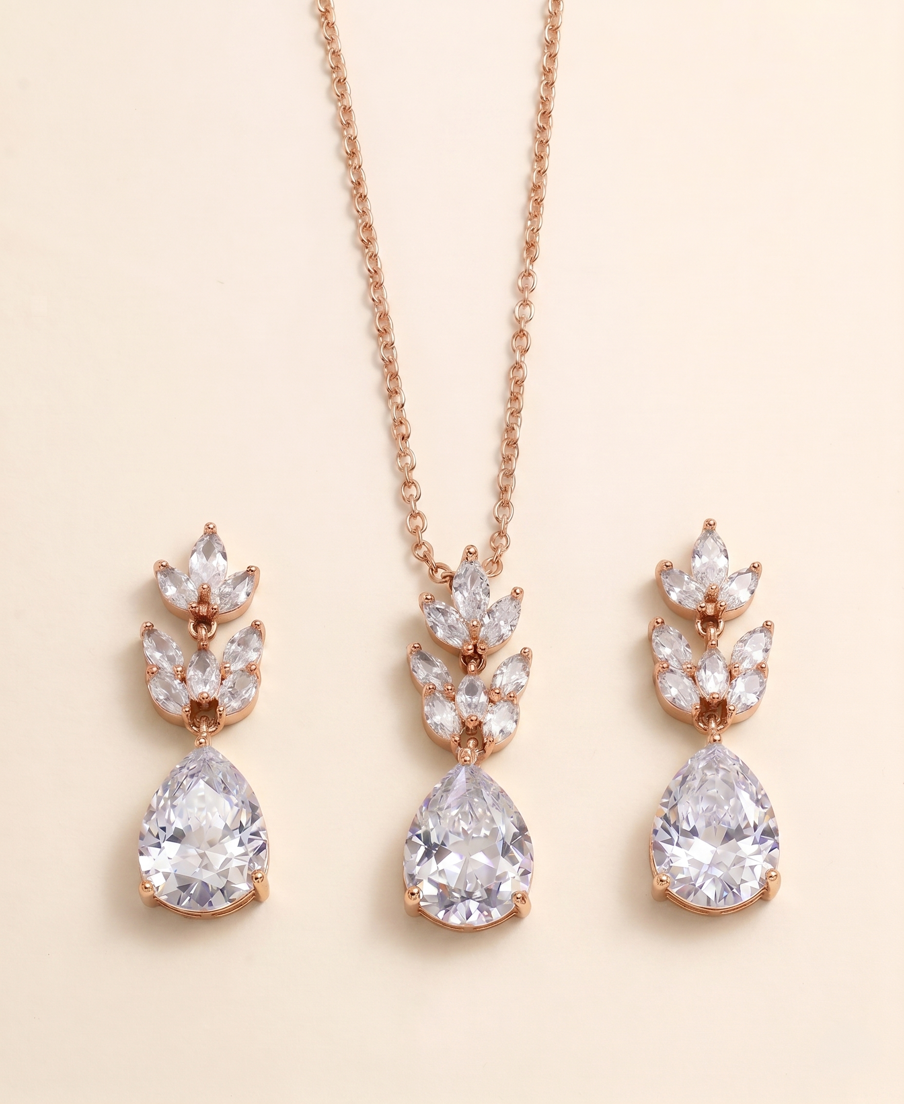 A necklace with a pendant and earrings with a leaf-shaped design, all featuring large, clear gemstones.