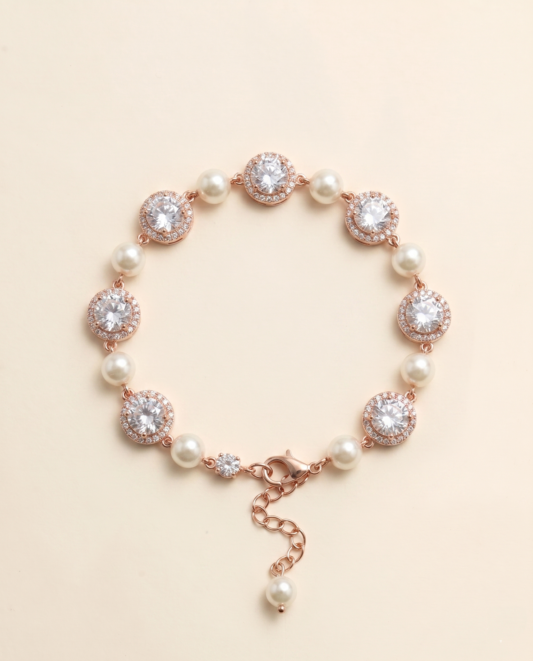 A bracelet with a clasp and a row of pearls and diamonds on a beige background.