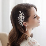 A woman with long, dark hair wearing a white lace dress and a decorative hair accessory.