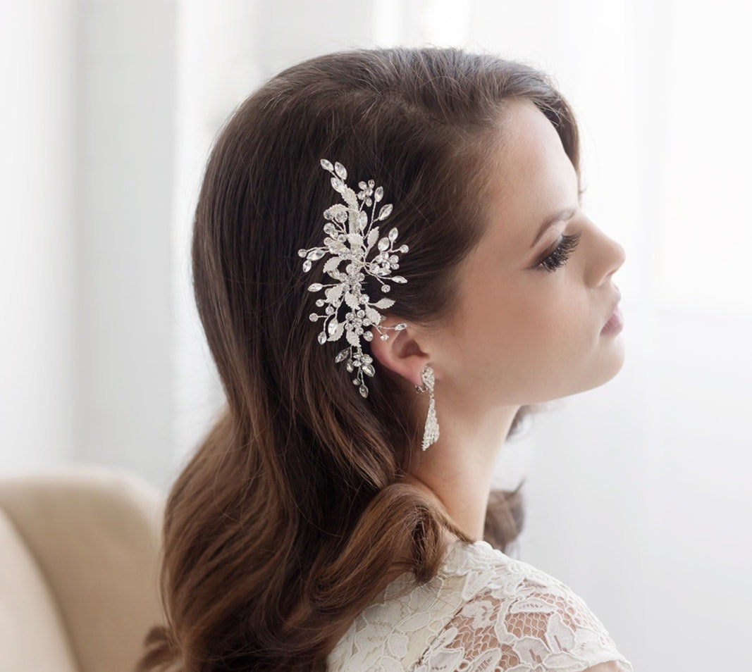 A woman with long, dark hair wearing a white lace dress and a decorative hair accessory.