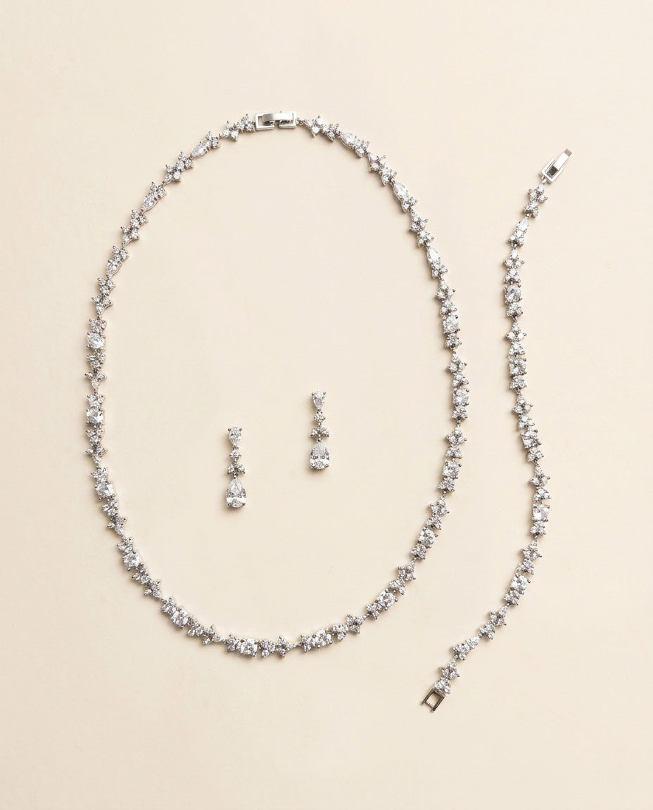 a necklace and earrings set made of sparkling diamonds arranged on a light-colored background.