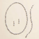 a necklace and earrings set made of sparkling diamonds arranged on a light-colored background.