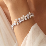 A close-up of a person's arm wearing a bracelet with pearls and diamonds.