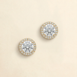 A pair of elegant earrings with large, clear gemstones set in a gold-colored halo.
