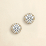 A pair of elegant earrings with large, clear gemstones set in a gold-colored halo.