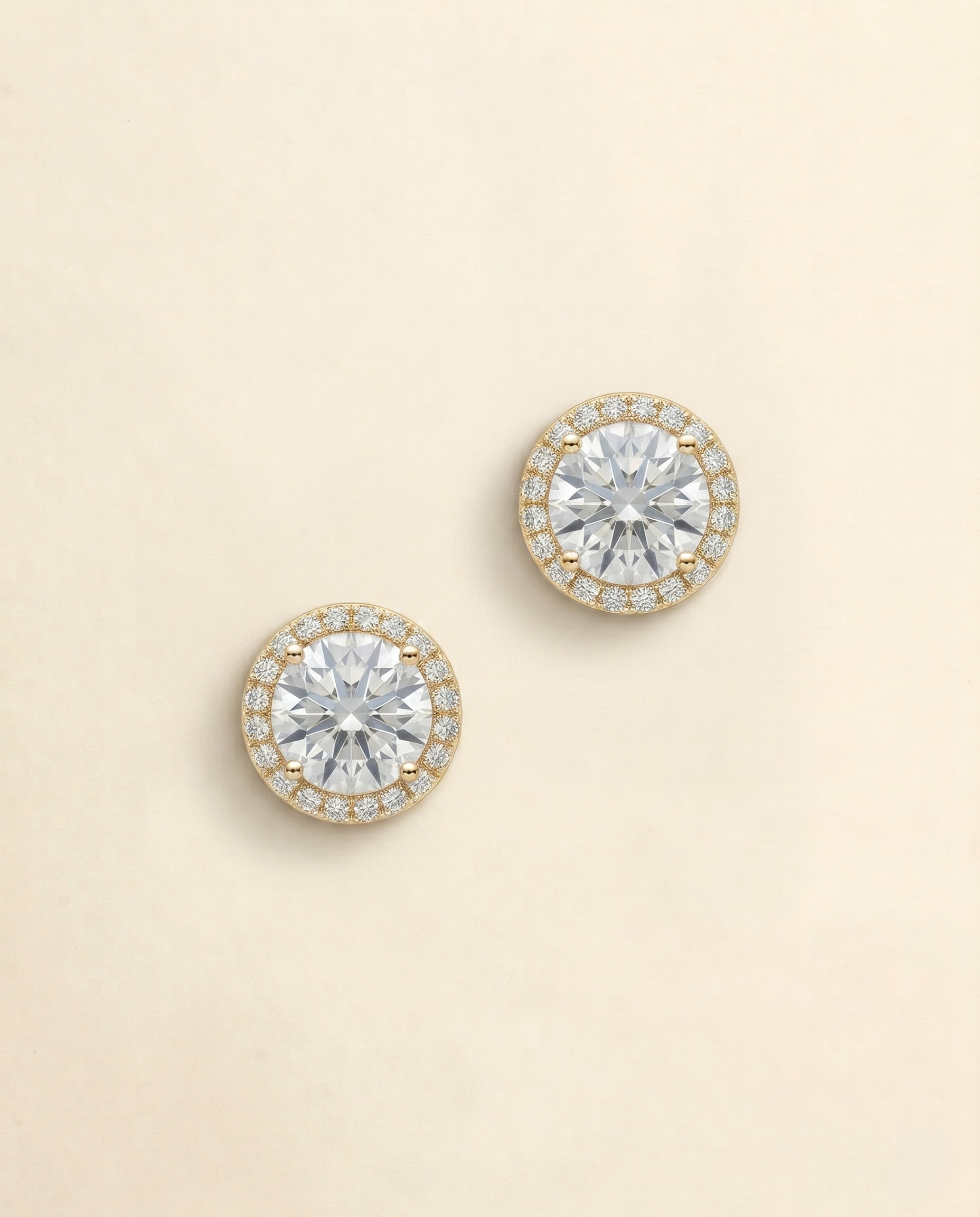 A pair of elegant earrings with large, clear gemstones set in a gold-colored halo.