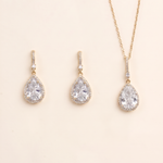 A set of three gold-colored jewelry pieces, including earrings and a necklace, featuring large, clear gemstones.