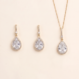 A set of three gold-colored jewelry pieces, including earrings and a necklace, featuring large, clear gemstones.