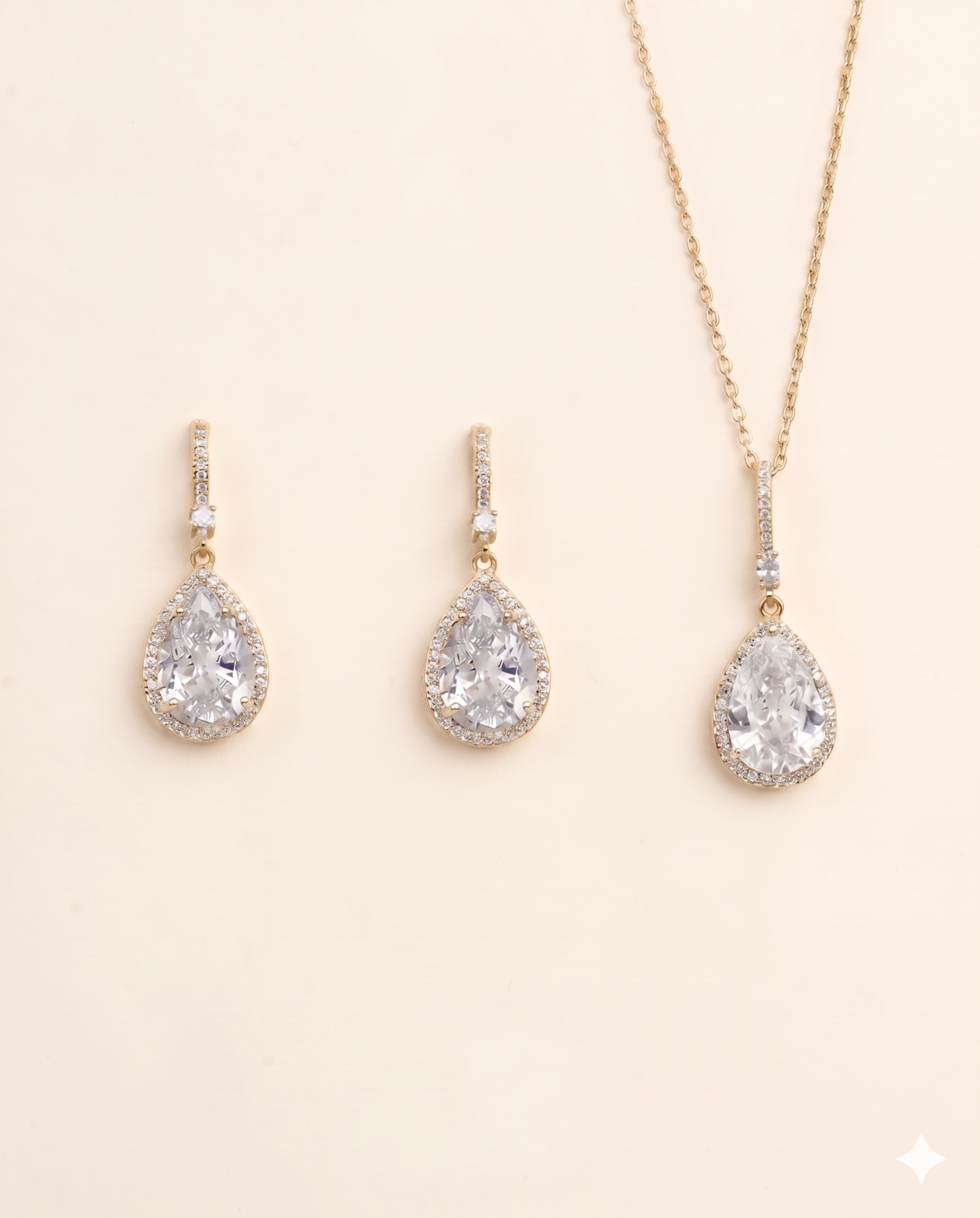 A set of three gold-colored jewelry pieces, including earrings and a necklace, featuring large, clear gemstones.