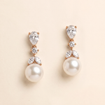 A pair of elegant pearl drop earrings with a delicate floral design and sparkling gemstones.