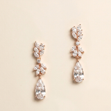 A pair of elegant gold earrings with large, clear gemstones hanging from the bottom.
